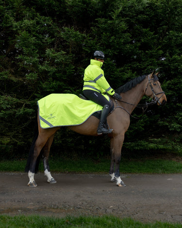 Person wearing a hi-vis waterproof jacket riding a horse with a hi-visibliity exercise sheet