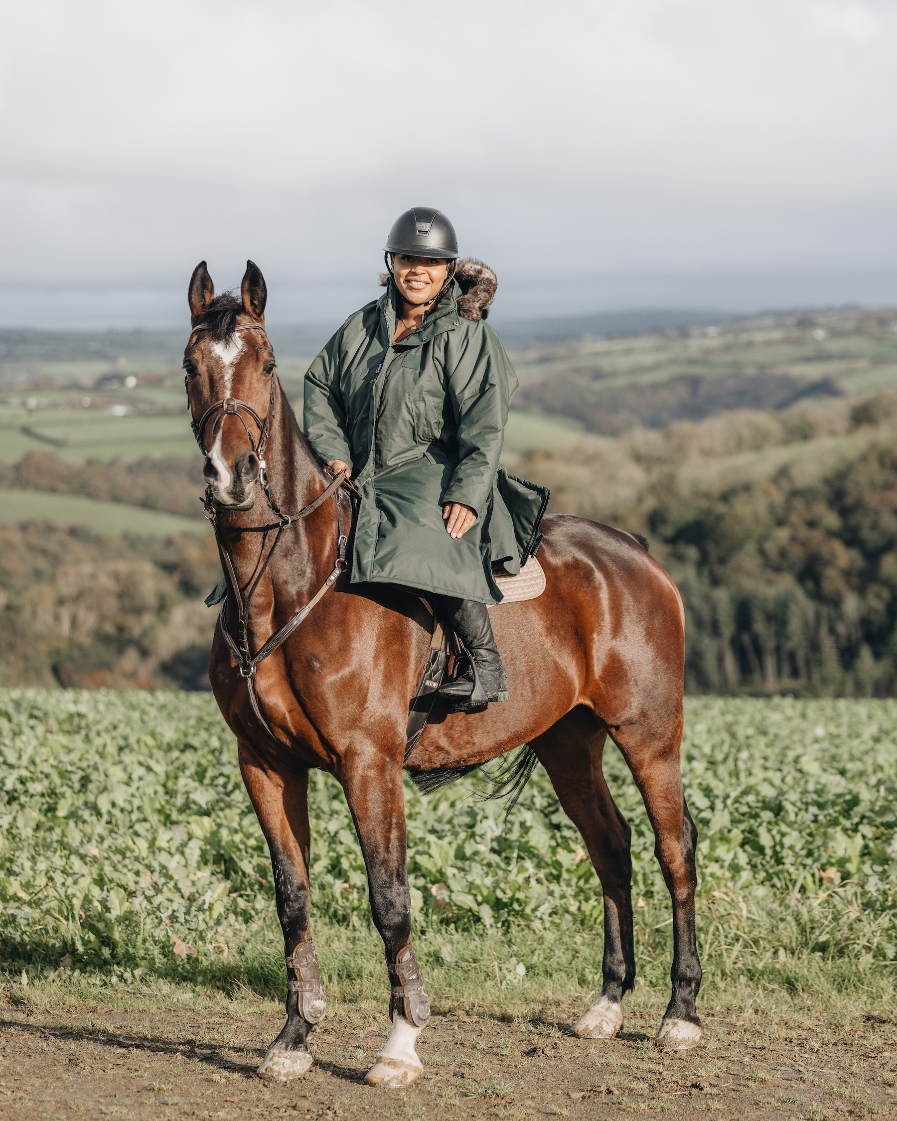 EQUIDRY Black Forest Green Parka  with fur hood modelled by woman riding Horse cross country 
