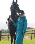 EQUIDRY women's long waterproof horse riding coat in turquoise stood with horse