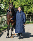 EQUIDRY women's long waterproof horse riding coat in navy/charcoal modelled by rider with horse