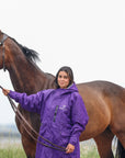 EQUIDRY women's long waterproof horse riding coat in deep purple/grey modelled by rider holding horse