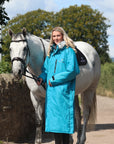 EQUIDRY Evolution Lux Women's Warm Waterproof Winter Horse Riding Coat Thick Fleece Lining with Faux Fur Trim Hood in turquoise rider full front view with horse 