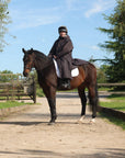 EQUIDRY women's long waterproof horse riding coat in rich brown/cream modelled by rider on horseback 