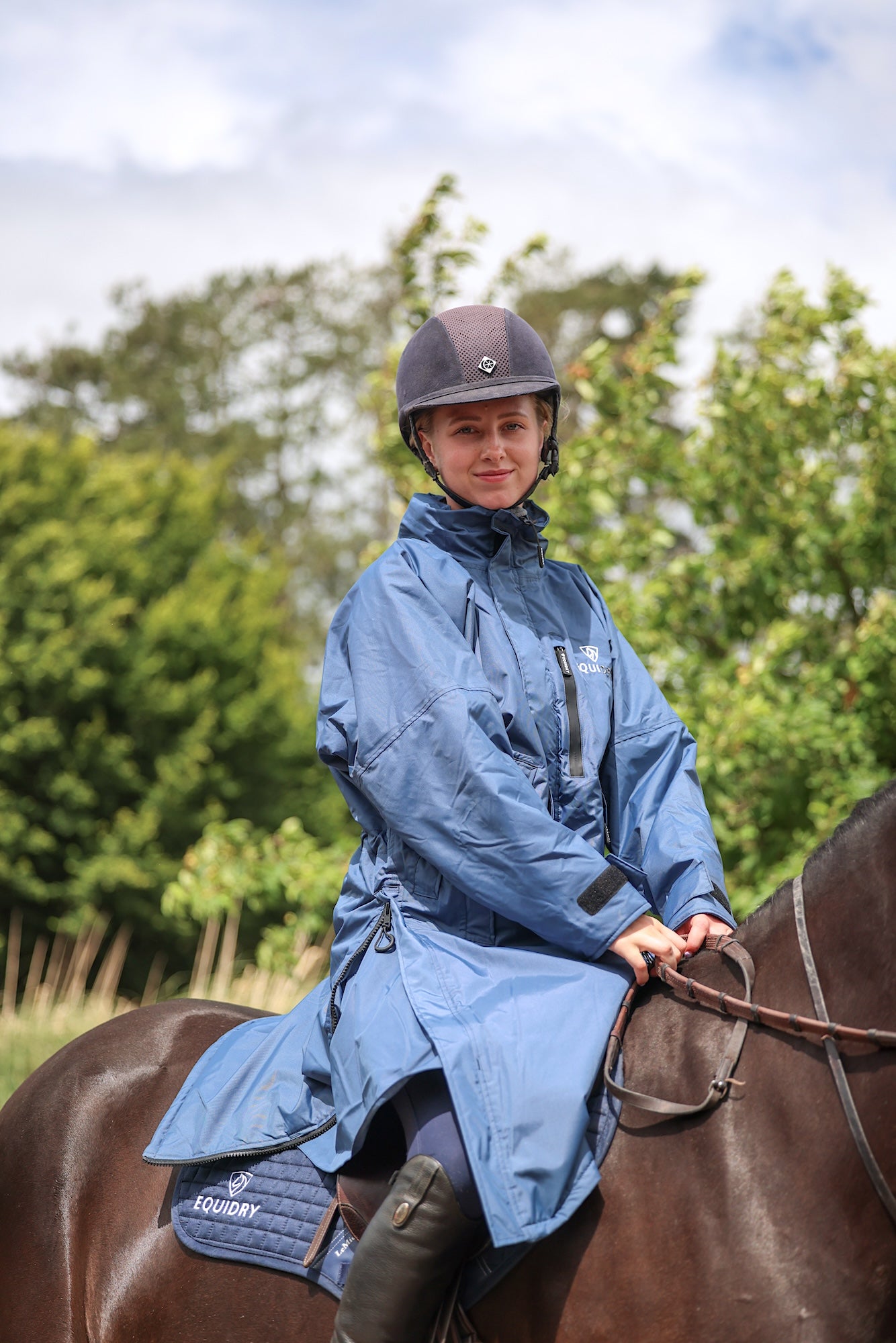 EQUIDRY women's thin fleece stowaway hood long waterproof horse riding coat in steel blue on horse