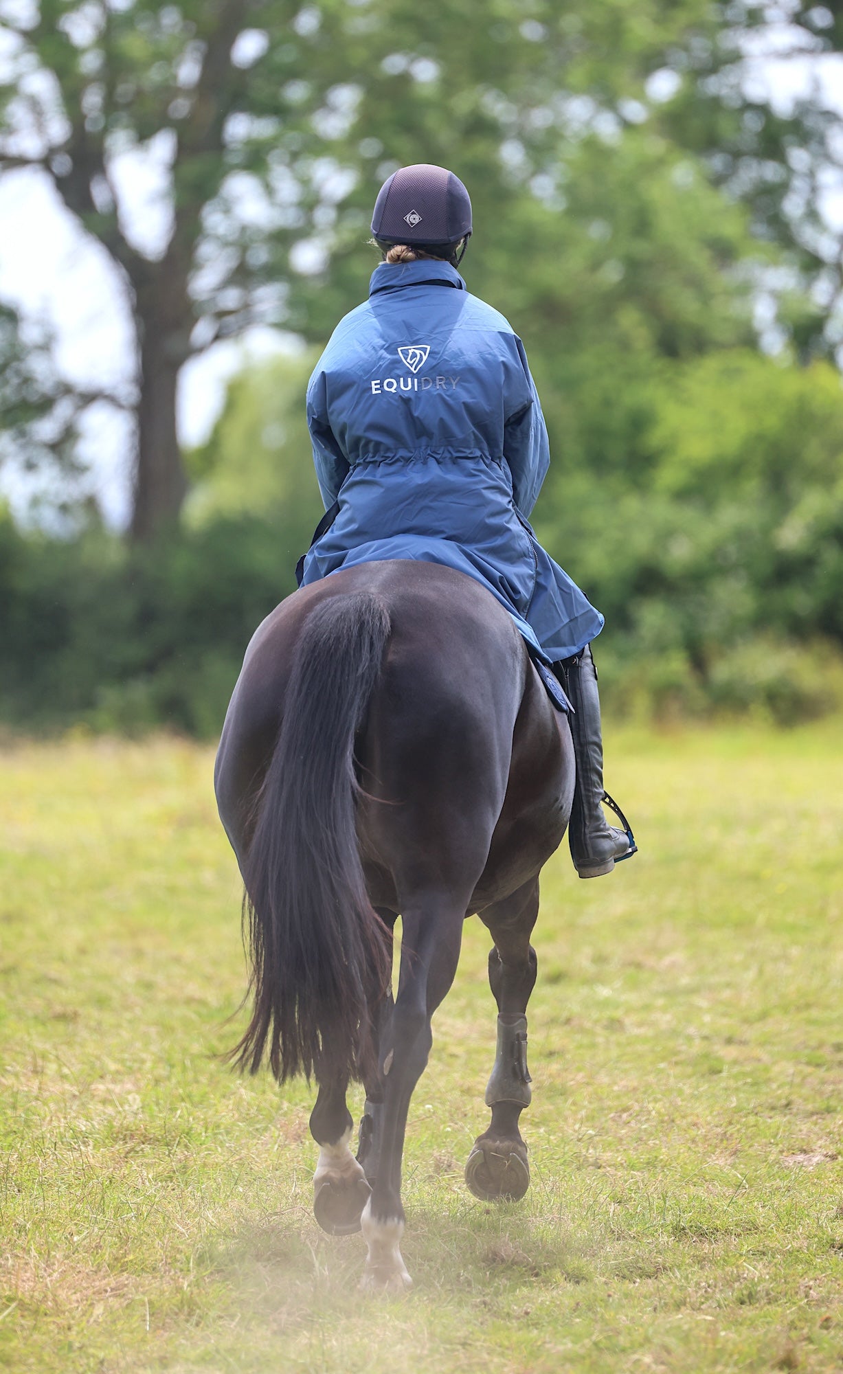 EQUIDRY women's thin fleece stowaway hood long waterproof horse riding coat in steel blue on horse behind 