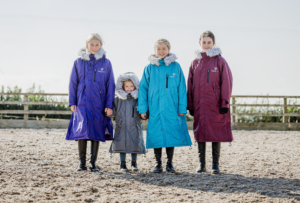 EQUIDRY Evolution Lux children's Warm Waterproof Winter Horse Riding Coat Thick Fleece Lining with Faux Fur Trim Hood being shown in purple, turquoise, plum/ charcoal/grey 