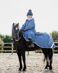 EQUIDRY Evolution Lux children's Warm Waterproof Winter Horse Riding Coat Thick Fleece Lining with Faux Fur Trim Hood being shown in steel blue on horse 