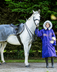 EQUIDRY Evolution Lux children's Warm Waterproof Winter Horse Riding Coat Thick Fleece Lining with Faux Fur Trim Hood being shown in purple by rider with horse in exercise sheet