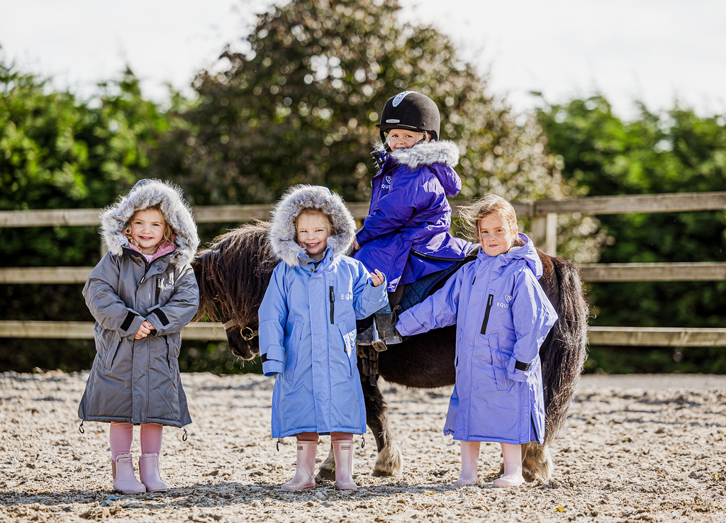 EQUIDRY Evolution Lux children&#39;s Warm Waterproof Winter Horse Riding Coat Thick Fleece Lining with Faux Fur Trim Hood being shown in purple, sky blue, charcoal/pale pink with kids on horse 