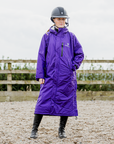 EQUIDRY women's long waterproof horse riding coat in deep purple modelled by rider in arena 