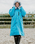 EQUIDRY Evolution Lux Women's Warm Waterproof Winter Horse Riding Coat Thick Fleece Lining with Faux Fur Trim Hood in turquoise rider stood with hood up