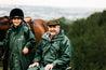 Black Forest Green EQUIDRY Equomac long waterproof raincoat worn by young horse rider and older man