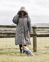 EQUIDRY Charcoal Parka with fur hood, long riding coat modelled by woman walking dog  in countryside