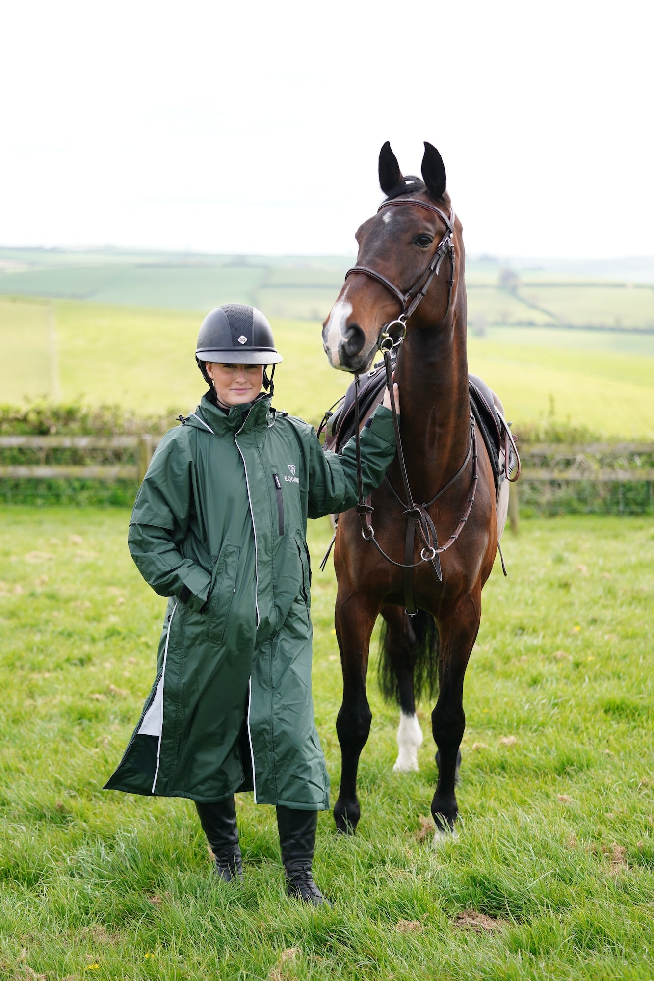 EQUIDRY waterproof horse riding raincoat thin fleece pro ride reflective black forest green rider stood with horse full front view 