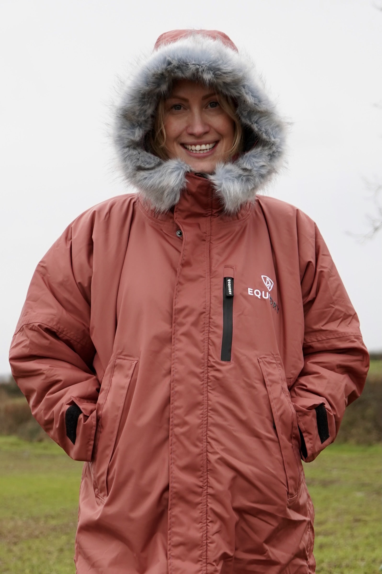 All Rounder Lux Chestnut EQUIDRY Equestrian oversized waterproof Horse Riding Coat with side zips modelled by a walker in the countryside