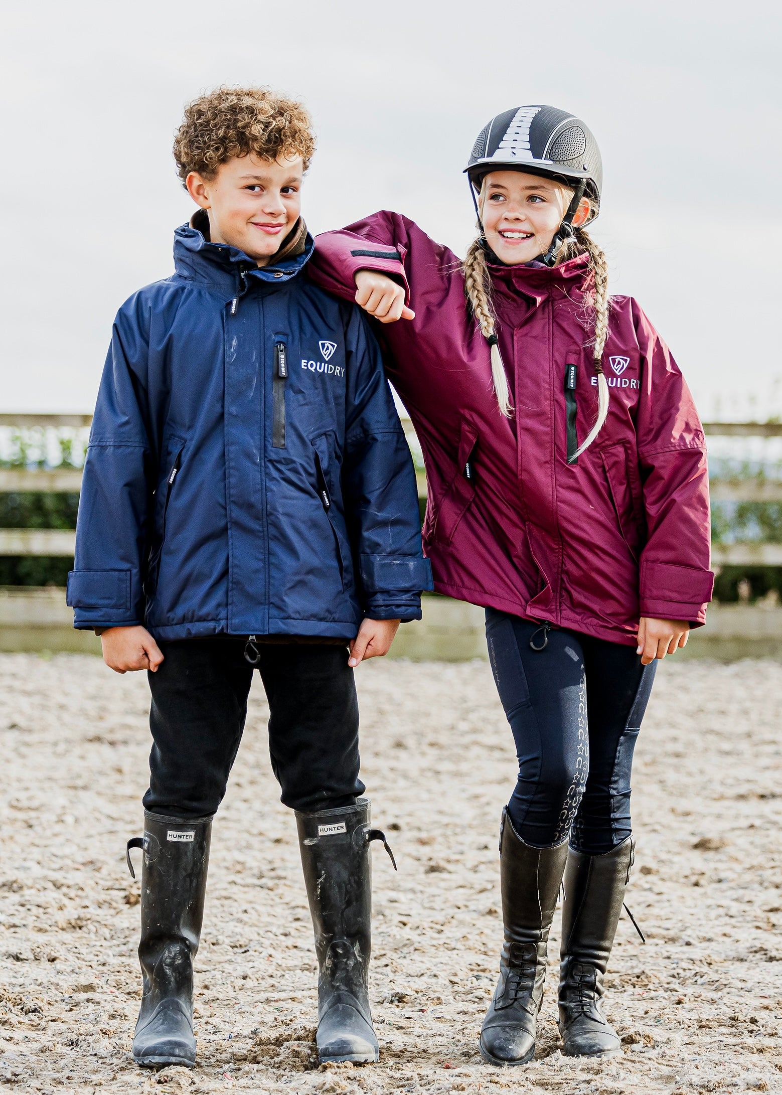 Shortie Child's Oversized Short Waterproof Riding Jacket Thin Fleece Lining Stowaway Hood in plum and navy worn by kids in arena 