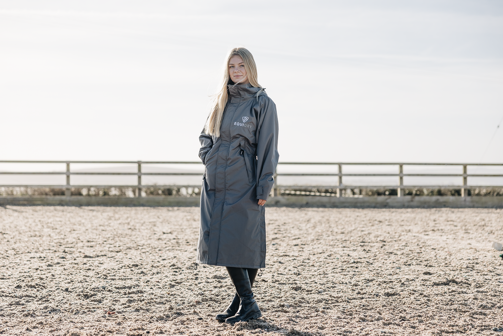 EQUIDRY Charcoal Equimac long waterproof lightweight riding coat modelled by female horse riding instructor 