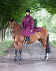 EQUIDRY women's thin fleece stowaway hood long waterproof horse riding coat in plum on horse