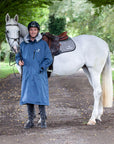 Evolution Lux Men's Warm Waterproof Horse Riding Coat in steel blue worn by male rider stood with horse 