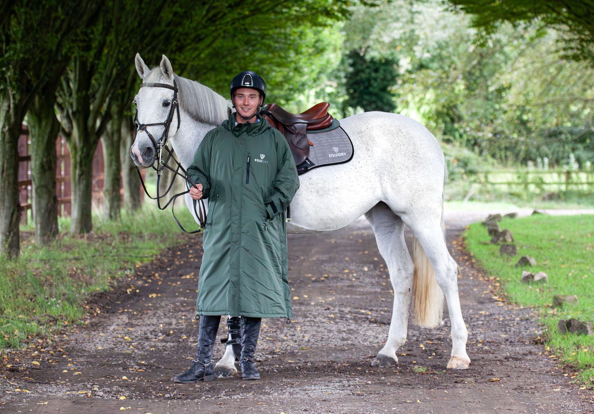 Evolution Pro men&#39;s Warm Waterproof Horse Riding Coat Thick Fleece Lining Stowaway Hood in Black Forest Green/Grey male rider stood with horse