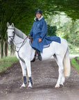 Evolution Lux Men's Warm Waterproof Horse Riding Coat in steel blue modelled by male rider on horseback showing storm skirts and side zips