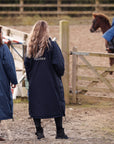 EQUIDRY women's long waterproof horse riding coat in navy/cream mums stood spectating riding lesson by arena, back of coats 