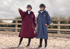 EQUIDRY Pro Ride Evolution Equestrian oversized waterproof Horse Riding Coat in Navy and plum modelled by rider's course walking a  jumping arena 