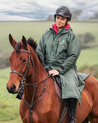 EQUIDRY women's long waterproof horse riding coat in black forest green/peacock pink shown by rider out hacking on horse