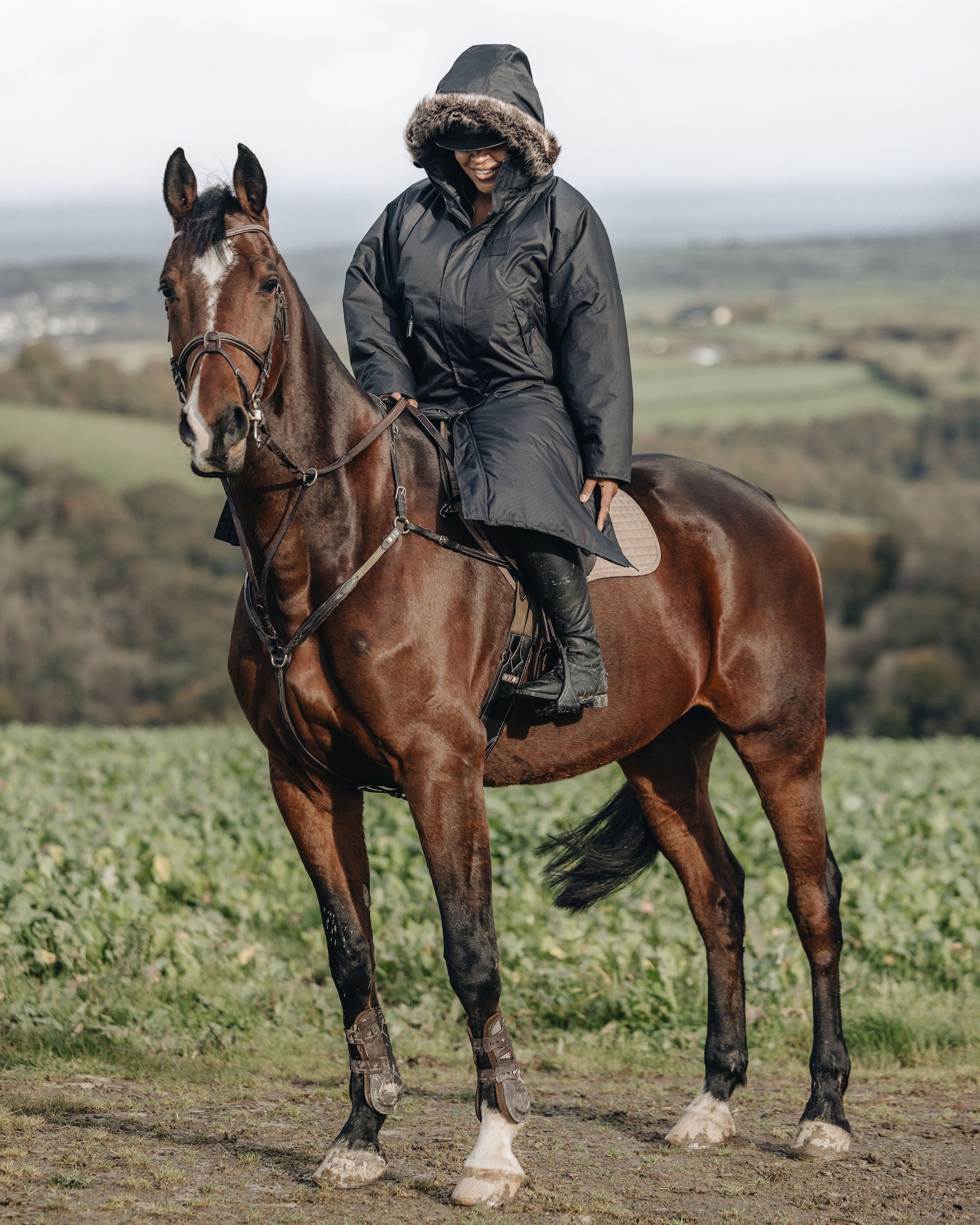 EQUIDRY Black Parka  with fur hood modelled by woman riding Horse cross country 