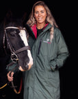 EQUIDRY women's long waterproof horse riding coat in  Black Forest Green/Peacock Pink shown by groom with horse