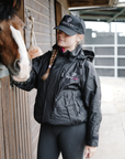 EQUIDRY women's waterproof short blouson style horse riding jacket in black/peacock pink with horse on the yard